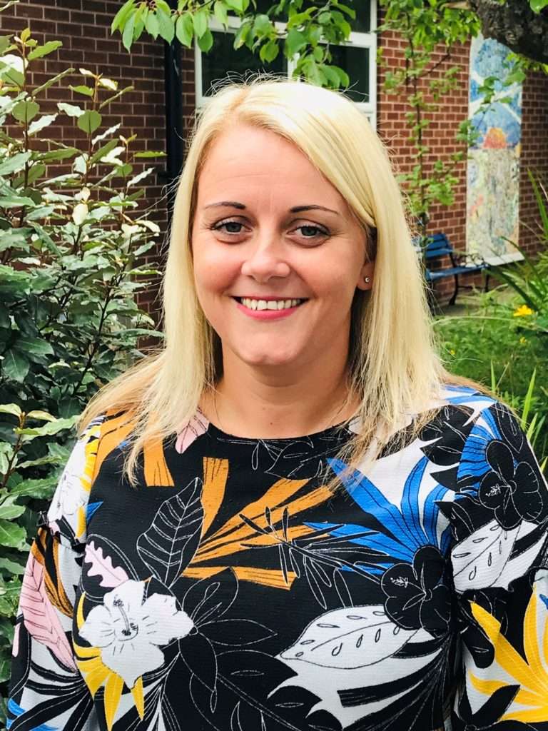 Mrs. Roberts, Headmaster Forefield Community School, smiling outdoors in front of a brick building